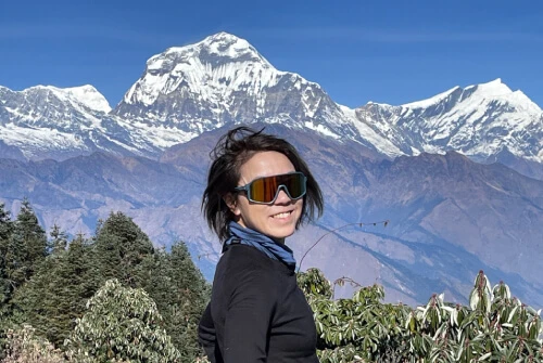 Solo female trekker walking on the Annapurna trail with Dhaulagir 8,167m in the background.