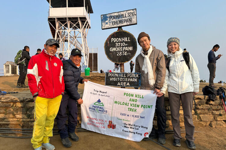 Trekkers taking picture at Poon Hill viewpoint after watching the sunrise over the Himalayas